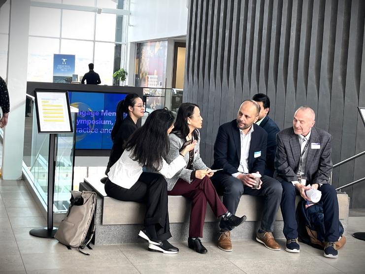 Conference attendees share their thoughts while seated on a bench.